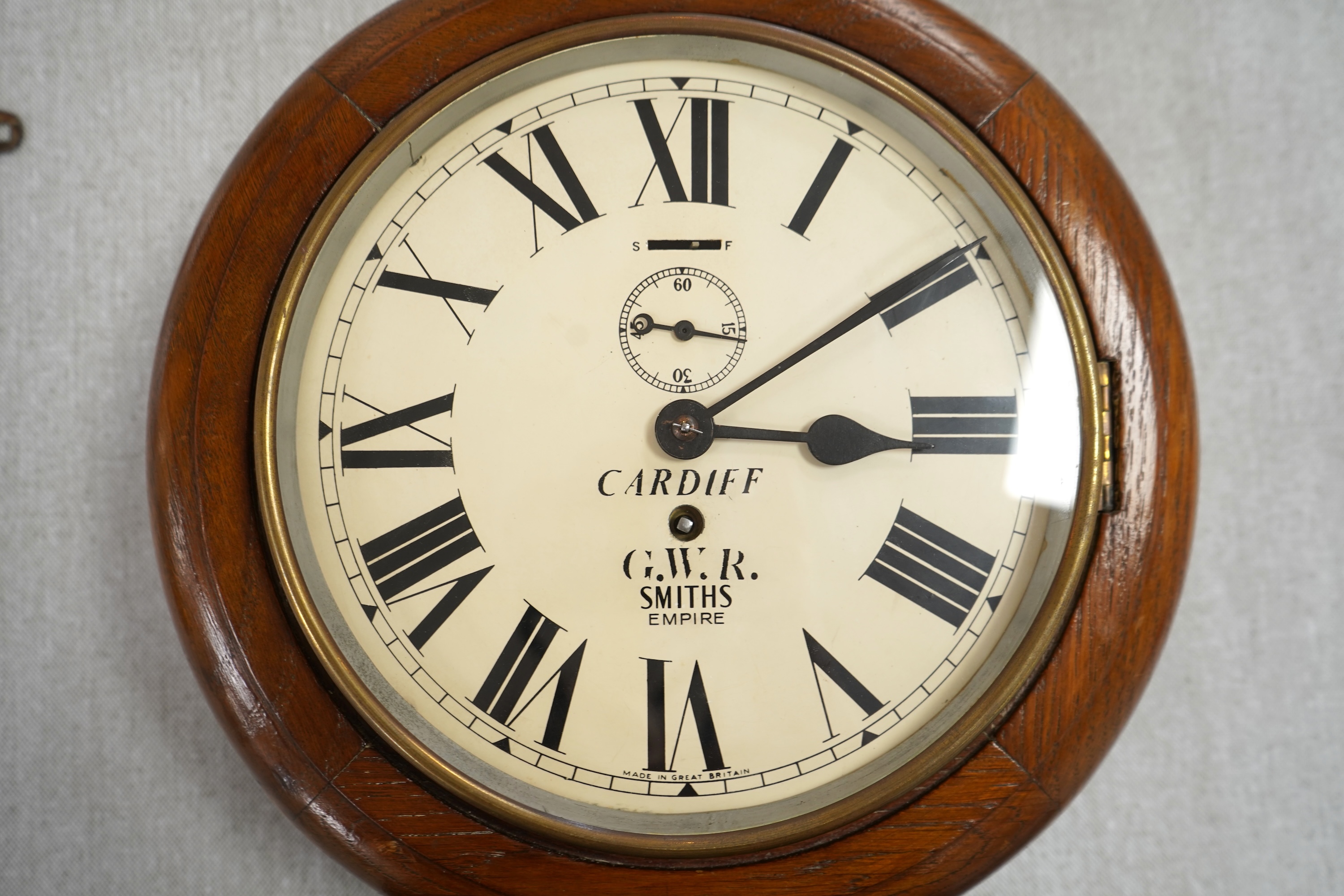 A GWR mahogany wall timepiece by Smiths, Made in Great Britain, with 8” painted dial marked Cardiff and separate seconds dial within the chapter ring, platform escapement, ivorine plaque engraved with ‘BR-WR 3952’ to the